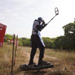 Deminer Souleye using matramine and metal detector on a test field at the entrance of Diagnon Village, East of Ziguinchor. Matramines are a security tool: they are air-blown shoes that spread the weight of deminer body then preventing to trigger landmine / Le démineur Souleye en train de tester le matériel (matramines et détecteur de métaux) sur une zone de test à l'entrée du village du Diagnon, à l'est de Ziguinchor. Les matramines sont des chaussures gonflées à l'air qui en répartissant le poids du corps du démineur empêchent de déclencher une mine.